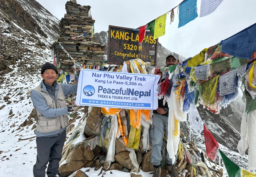 Trekkers holding a Peaceful Nepal banner at Kang La Pass (5,320 meters) on the Nar Phu Valley Trek