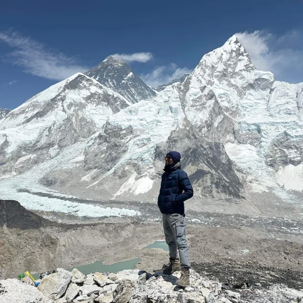 Trekker standing at Kala Patthar viewpoint with panoramic views of Mount Everest, Nuptse, and the Khumbu Glacier in the Everest region of Nepal.