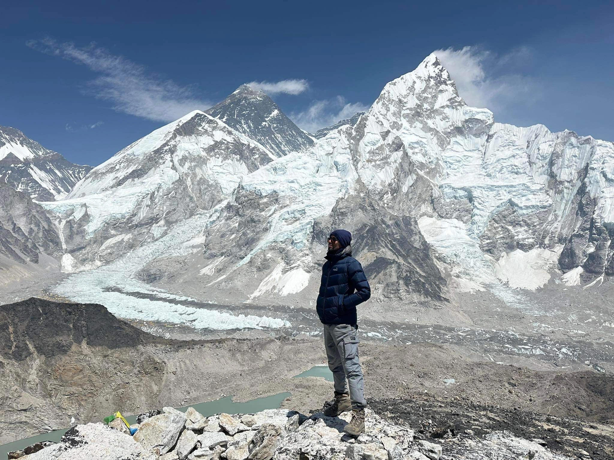 Trekker standing at Kala Patthar viewpoint with panoramic views of Mount Everest, Nuptse, and the Khumbu Glacier in the Everest region of Nepal.