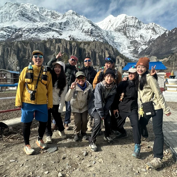 Group of trekkers posing in Manang, Nepal, with snowy Himalayan mountains