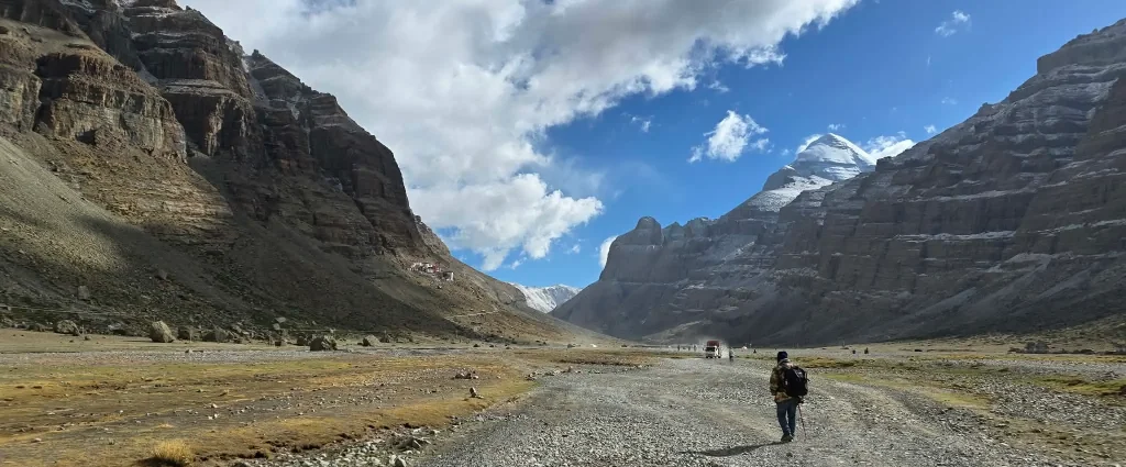 How Difficult Is Mount Kailash Tour: Pilgrim walking toward Mount Kailash through a dramatic valley in Shizang.