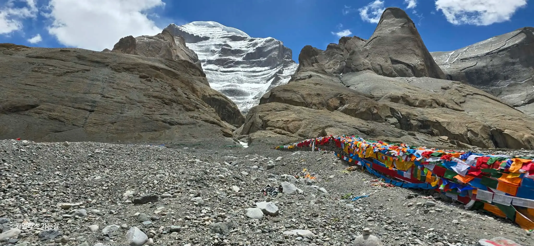Mount Kailash and colorful prayer flags in Shizang under a clear blue sky.