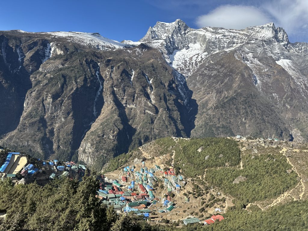 Traditional buildings in Namche Bazaar with towering Himalayan peaks behind.